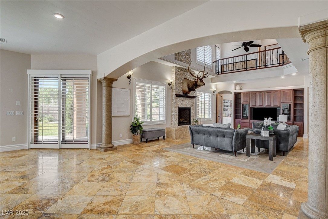 1182 Thomas Bay Circle Logandale, NV 89021 - Photo 33 of 98 Living area featuring arched walkways, ornate columns, a ceiling fan, and a recently remodeled fireplace
