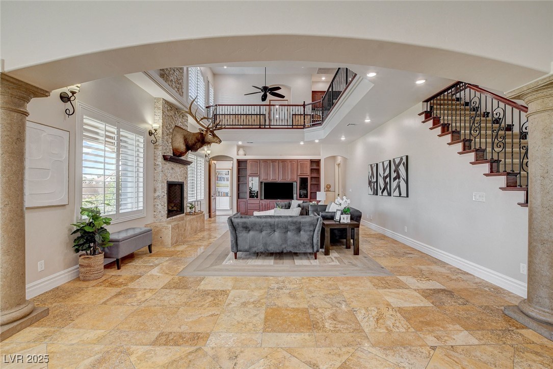 1182 Thomas Bay Circle Logandale, NV 89021 - Photo 34 of 98 Living room with a towering ceiling, ceiling fan, a stone fireplace, and arched walkways