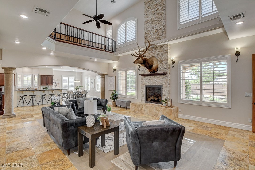 1182 Thomas Bay Circle Logandale, NV 89021 - Photo 4 of 98 Living room featuring arched walkways, a towering ceiling, decorative columns, a ceiling fan, and a fireplace
