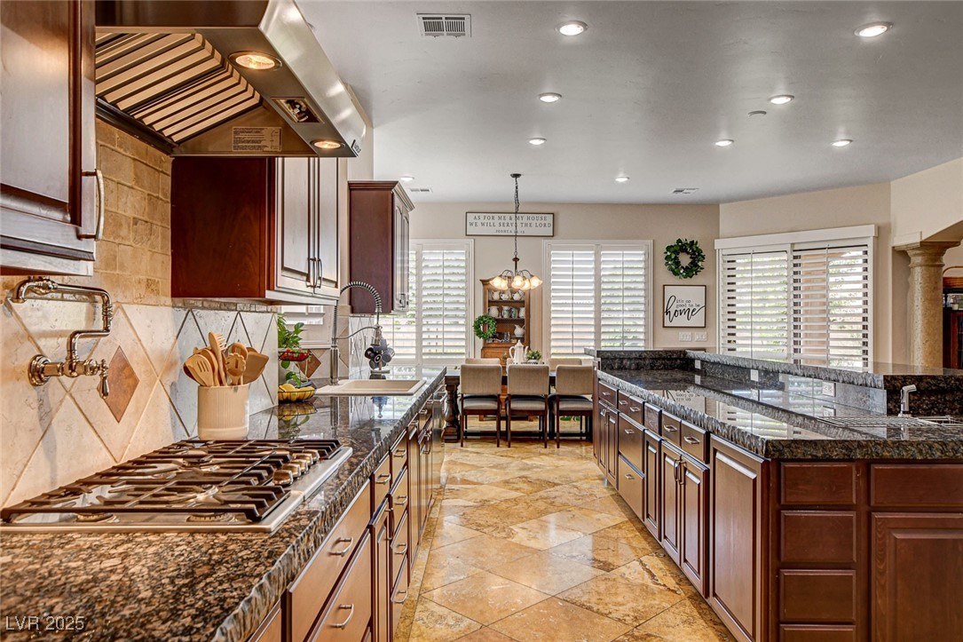 1182 Thomas Bay Circle Logandale, NV 89021 - Photo 5 of 98 Kitchen with exhaust hood, stainless steel gas cooktop, recessed lighting, decorative backsplash, and decorative light fixtures