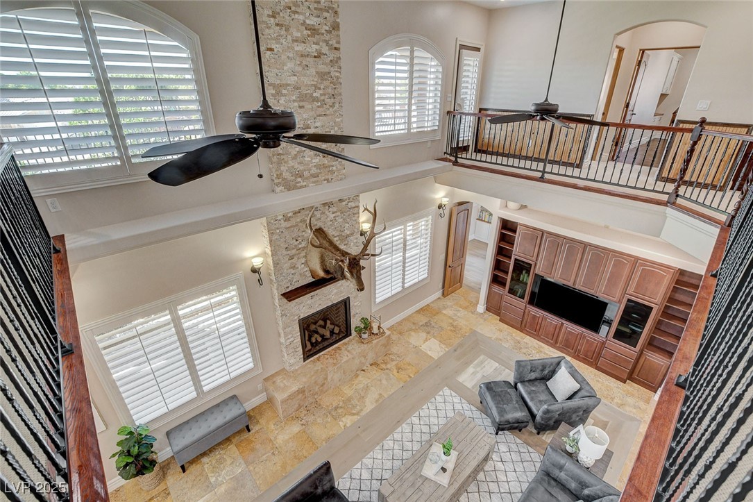 1182 Thomas Bay Circle Logandale, NV 89021 - Photo 53 of 98 Living room with a ceiling fan, a towering ceiling, arched walkways, and a recently added stone fireplace