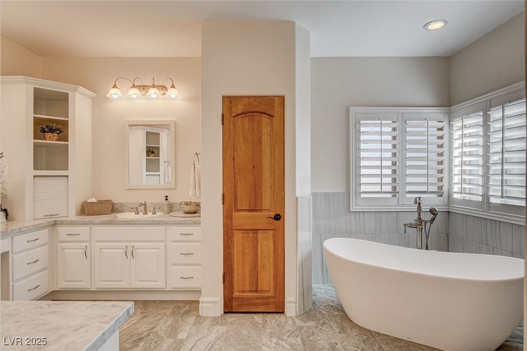 1182 Thomas Bay Circle Logandale, NV 89021 - Photo 70 of 98 Full bathroom with vanity, a freestanding tub, marble like finish floors, and tile walls