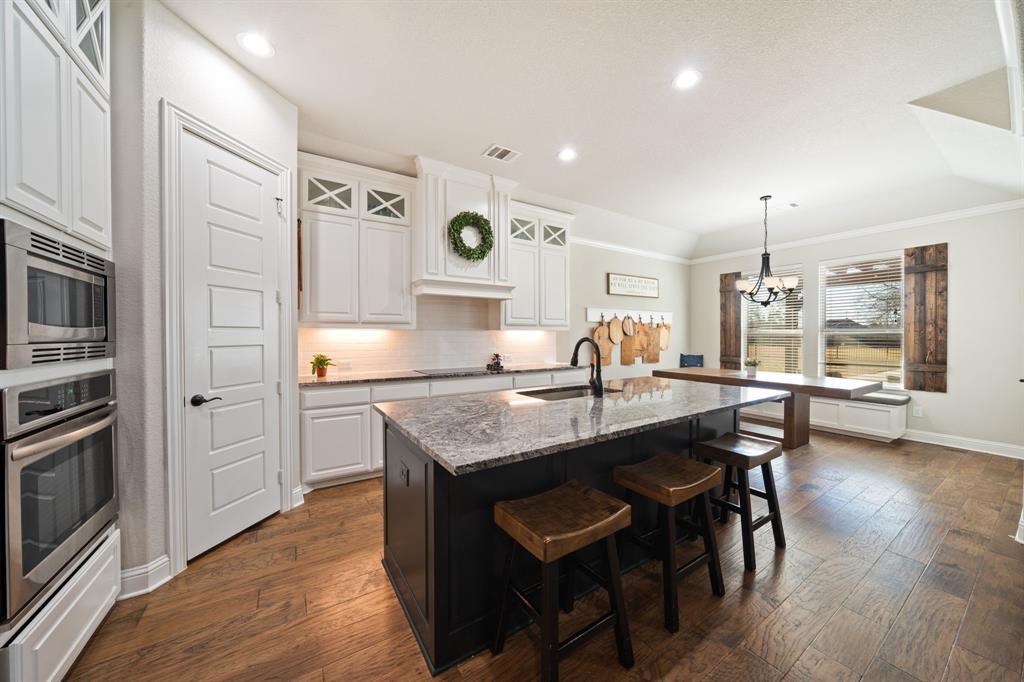 3601 Plainview Road Midlothian, TX 76065 - Photo 15 of 40 a kitchen with stainless steel appliances granite countertop a kitchen island hardwood floor sink stove dining table and chairs