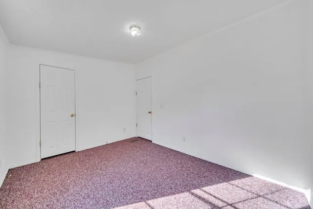 an empty room with windows and fireplace