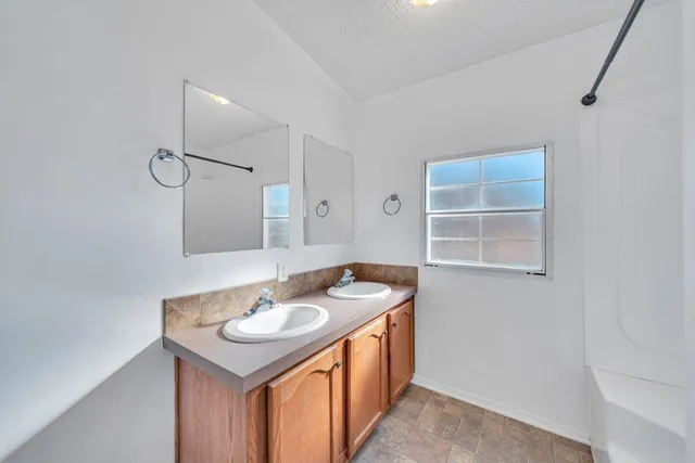 a view of an empty room with chandelier fan and wooden floor