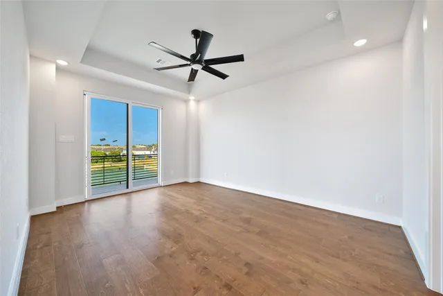 an empty room with wooden floor fan and windows