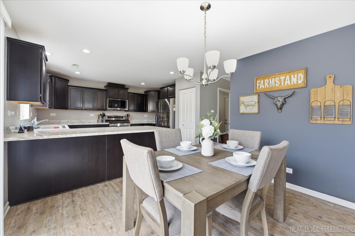 270 Norfolk Lane Pingree Grove, IL 60140 - Photo 9 of 25 a kitchen with stainless steel appliances kitchen island granite countertop a dining table chairs and a refrigerator