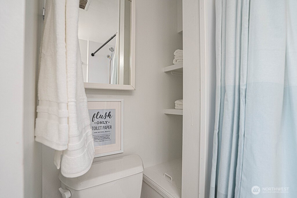4027 Beach Drive Southwest, Unit 1 Seattle, WA 98116 - Photo 17 of 28 a bathroom with a toilet and a shower curtain