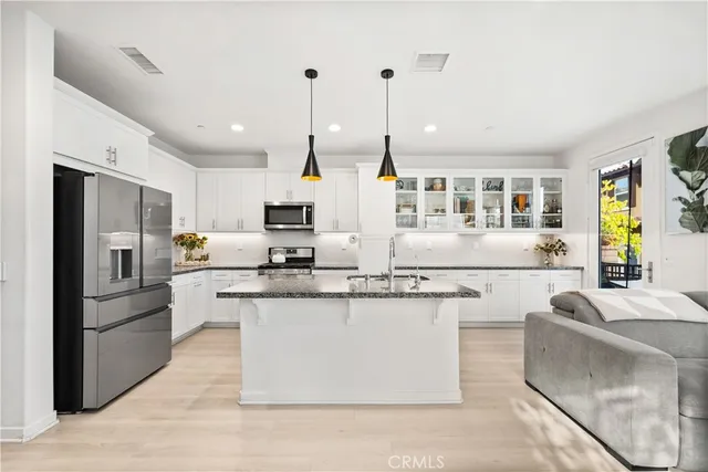 a kitchen with stainless steel appliances granite countertop a stove top oven a refrigerator a sink and white cabinets