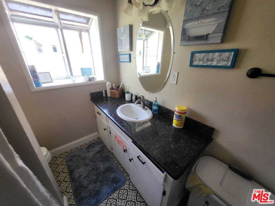 2831 Pine Street Bakersfield, CA 93301 - Photo 17 of 33 a bathroom with a granite countertop sink a toilet and a window