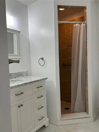 a bathroom with a granite countertop sink a mirror and shower