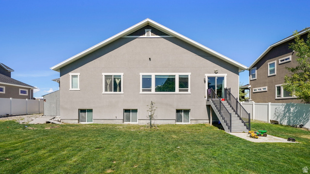 6062 Spring Street Stansbury Park, UT 84074 - Photo 28 of 36 Exterior featuring a stucco finish, multiple windows, and a sliding glass door leading to a deck with stairs to the yard
