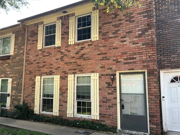 a brick building with a window and a tree