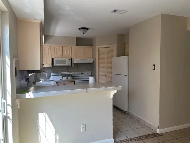a kitchen with kitchen island a white counter top space cabinets and stainless steel appliances