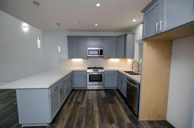a kitchen with stainless steel appliances granite countertop a stove a sink and a refrigerator