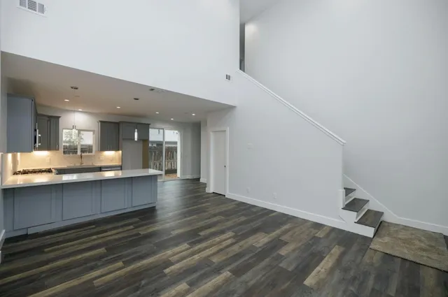 a large white kitchen with a sink and dishwasher a stove with wooden floor
