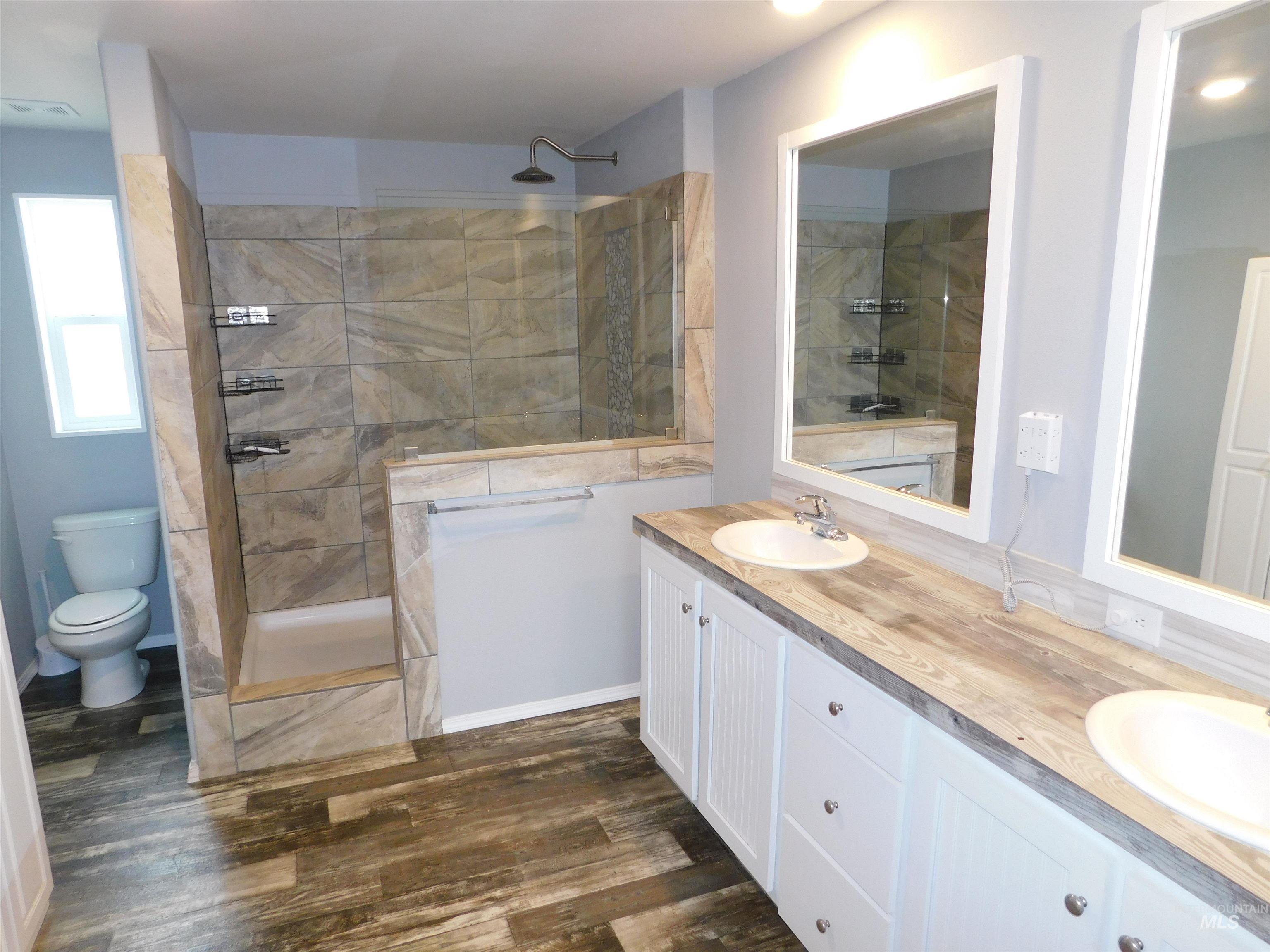 26915 Chips Lane Parma, ID 83660 - Photo 9 of 48 Full bathroom featuring double vanity, walk in shower, and dark wood-style floors
