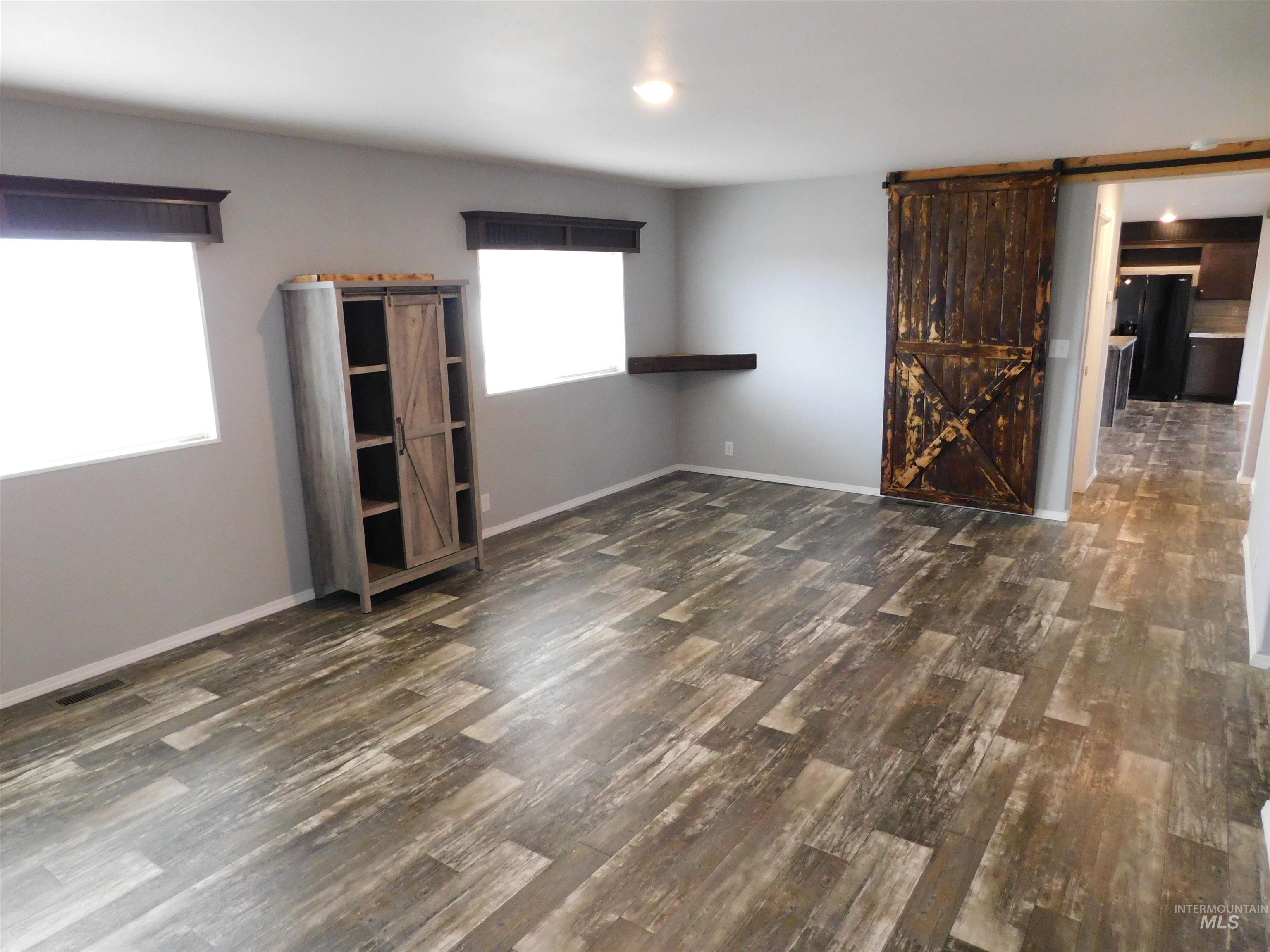 26915 Chips Lane Parma, ID 83660 - Photo 11 of 48 Empty room with a barn door and dark wood-type flooring