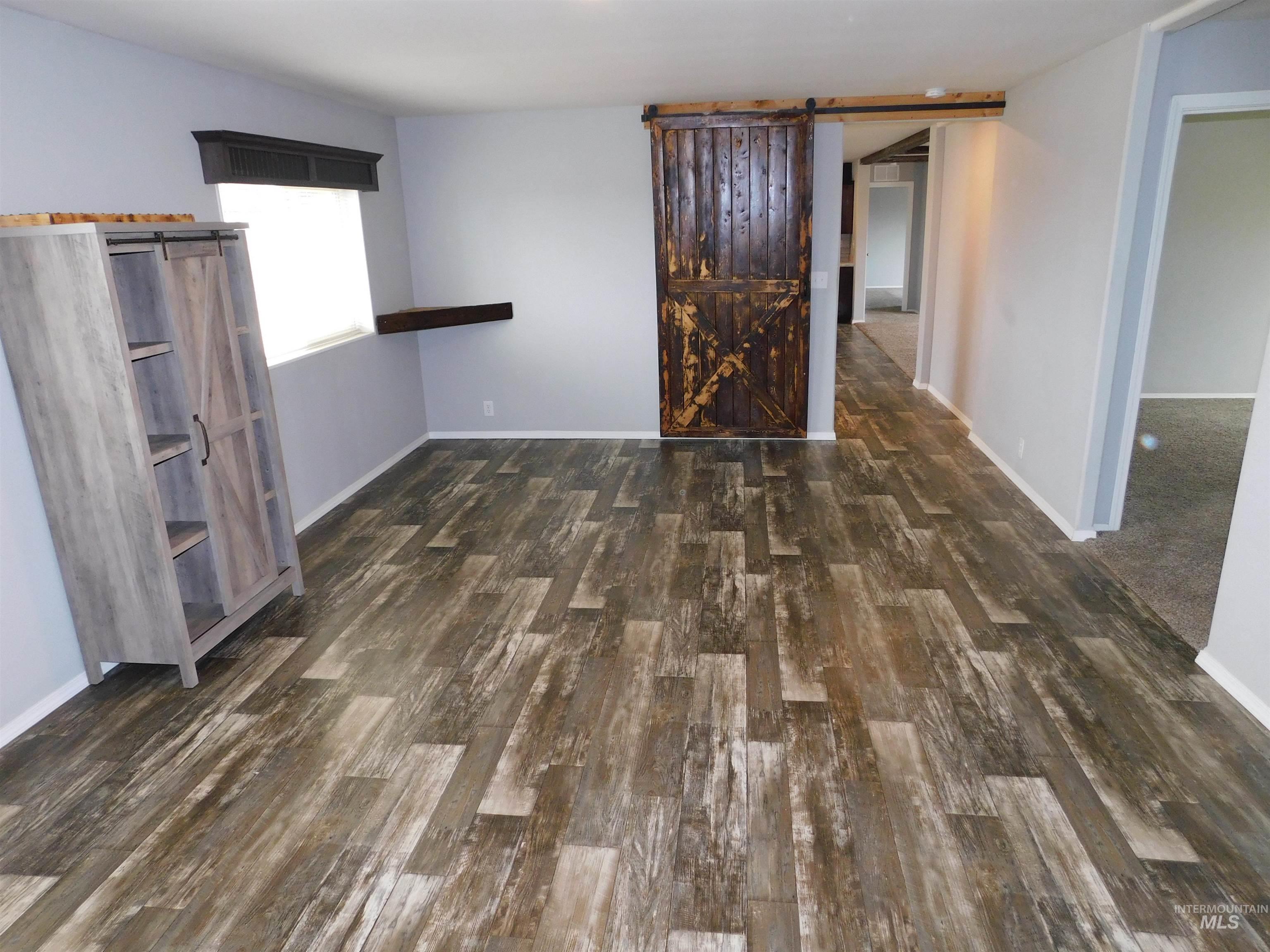 26915 Chips Lane Parma, ID 83660 - Photo 12 of 48 Unfurnished room featuring a barn door and dark wood-style flooring