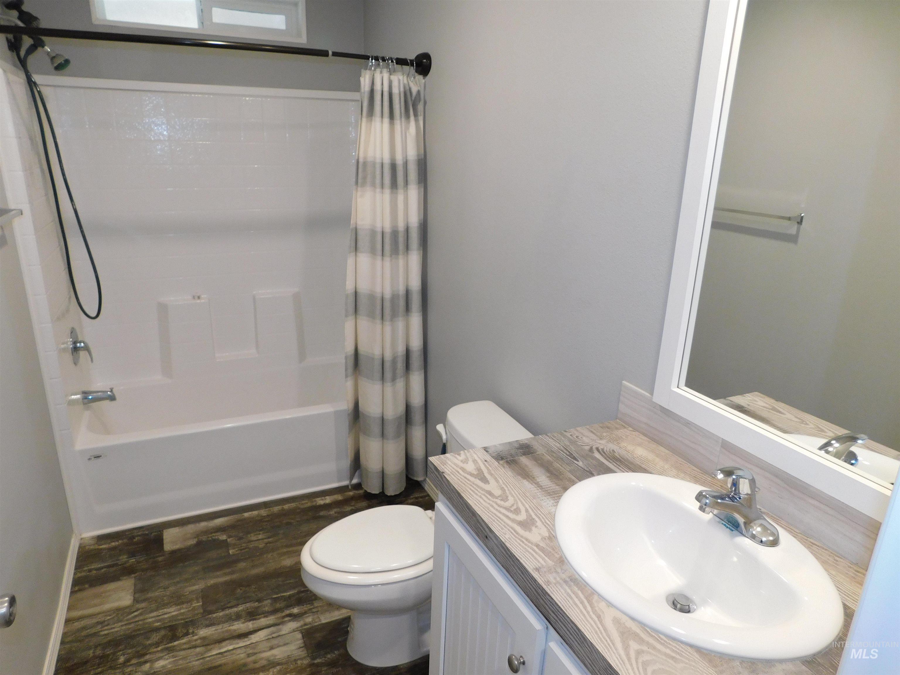26915 Chips Lane Parma, ID 83660 - Photo 15 of 48 Full bathroom featuring vanity, shower / bath combo with shower curtain, and dark wood-style floors