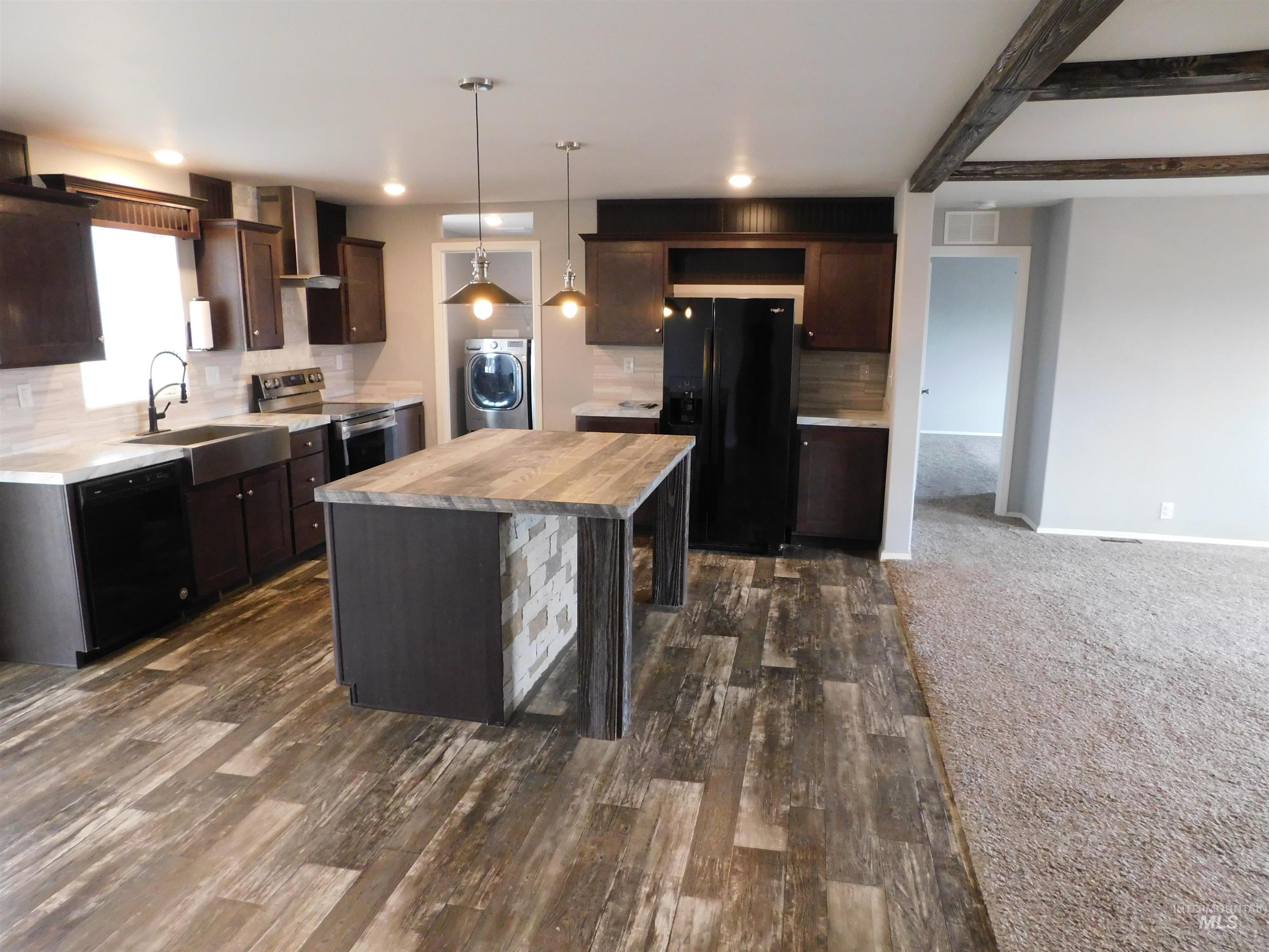 26915 Chips Lane Parma, ID 83660 - Photo 5 of 48 Kitchen with dark brown cabinetry, black appliances, a kitchen island, washer / clothes dryer, and pendant lighting