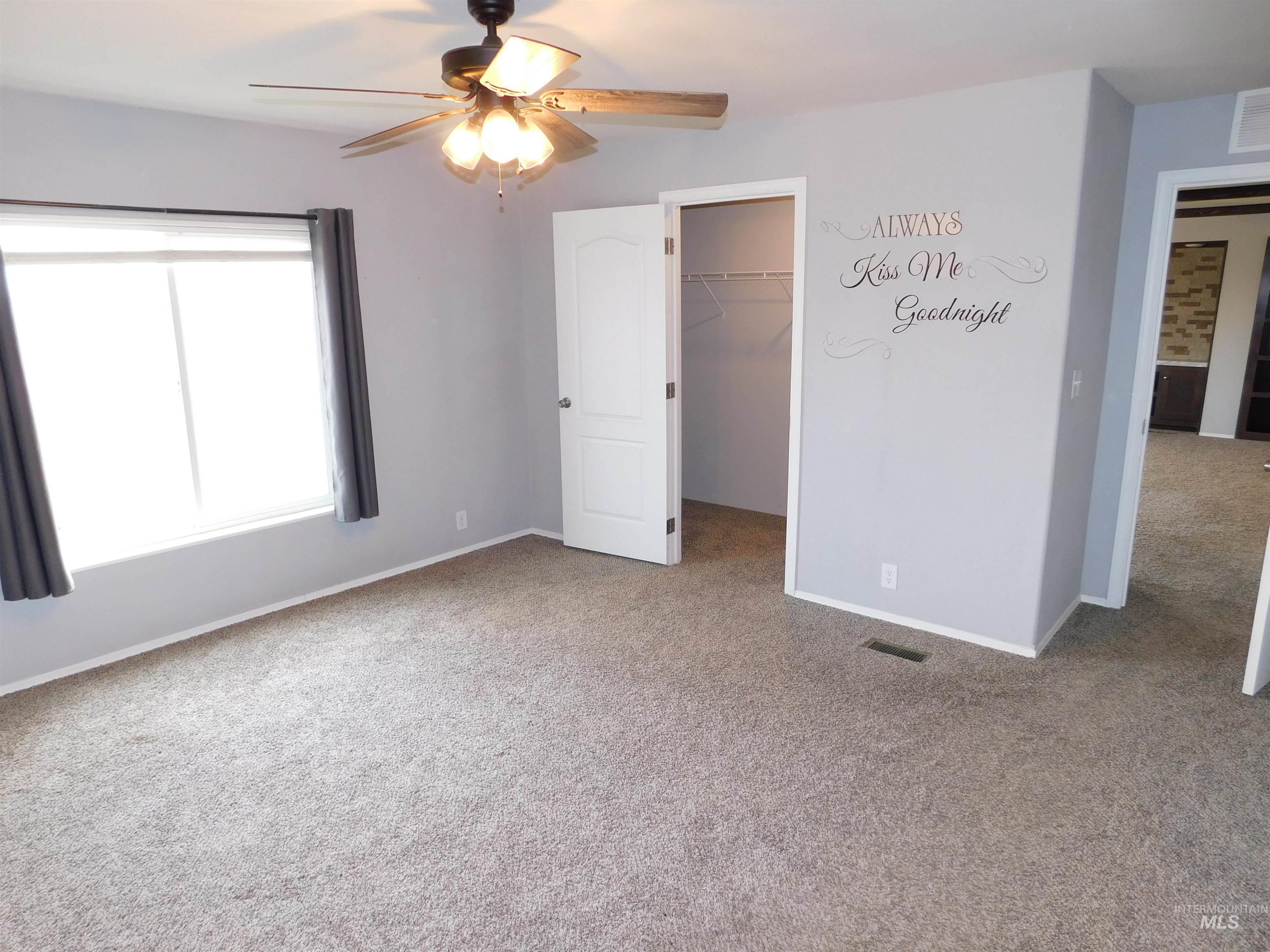 26915 Chips Lane Parma, ID 83660 - Photo 8 of 48 Unfurnished bedroom featuring light carpet, a walk in closet, and ceiling fan
