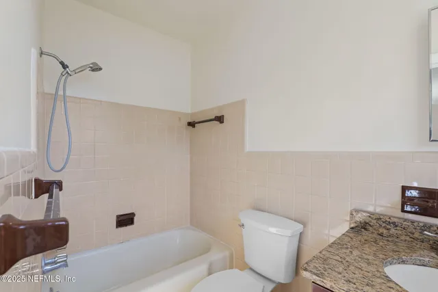 a bathroom with a granite countertop sink and a toilet