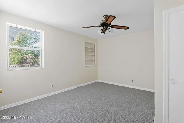 an empty room with windows and fan