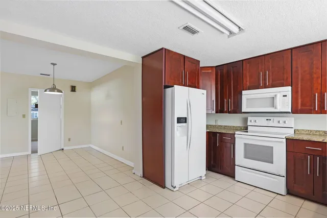 a kitchen with a refrigerator a stove top oven and cabinets