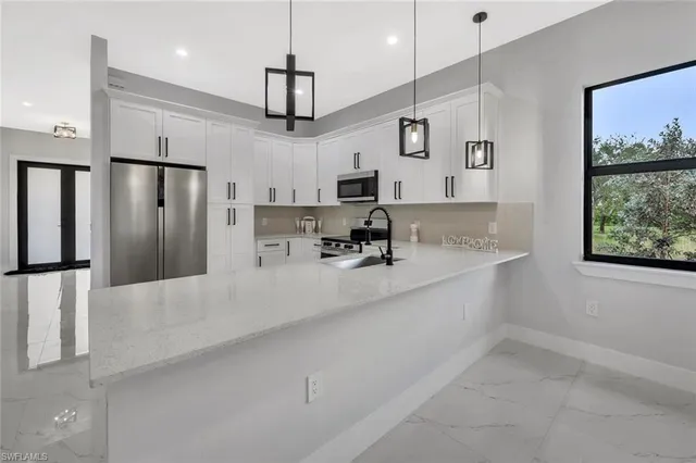 a large kitchen with kitchen island a large counter space a refrigerator and windows