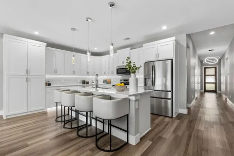 a kitchen with stainless steel appliances a refrigerator a stove a sink dishwasher and a dining table with wooden floor