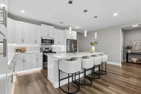 a kitchen with microwave a refrigerator and chairs