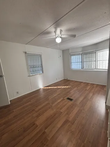 a view of empty room with wooden floor and fan