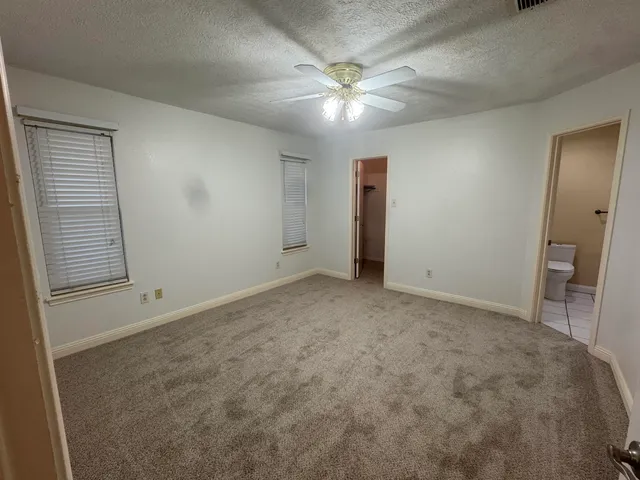 an empty room with a chandelier fan and windows