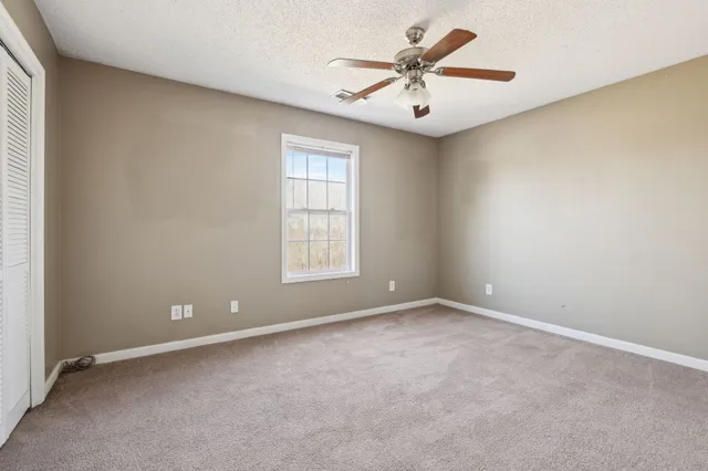 an empty room with windows and fan