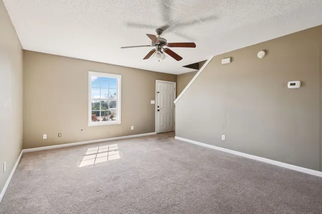an empty room with windows and fan