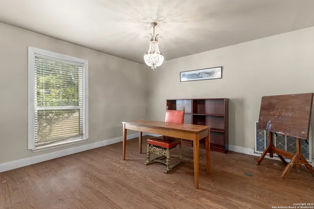 a view of a workspace with furniture a chandelier and wooden floor