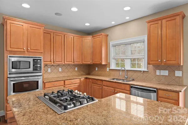 a kitchen with stainless steel appliances granite countertop a stove a sink and a microwave