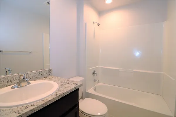 a bathroom with a granite countertop sink toilet and bathtub