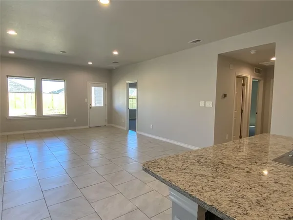 an empty room with kitchen view and windows