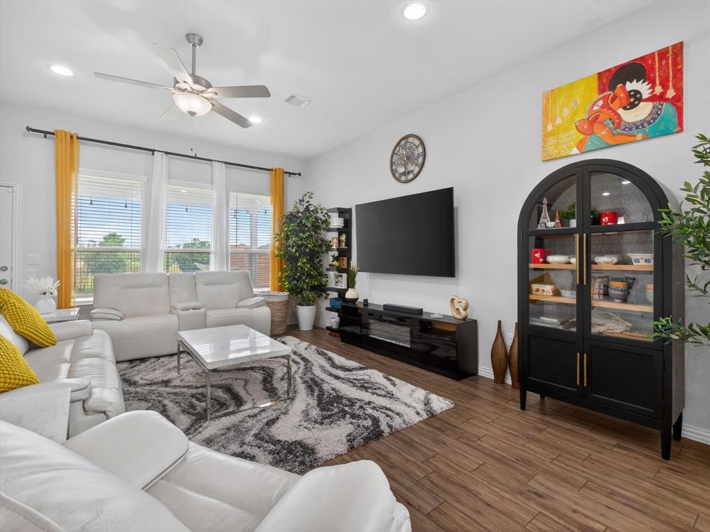 636 Corner Post Path Celina, TX 75009 - Photo 7 of 40 Spacious living area featuring wood-finish flooring, ample natural light from three large windows, recessed lighting, and a ceiling fan