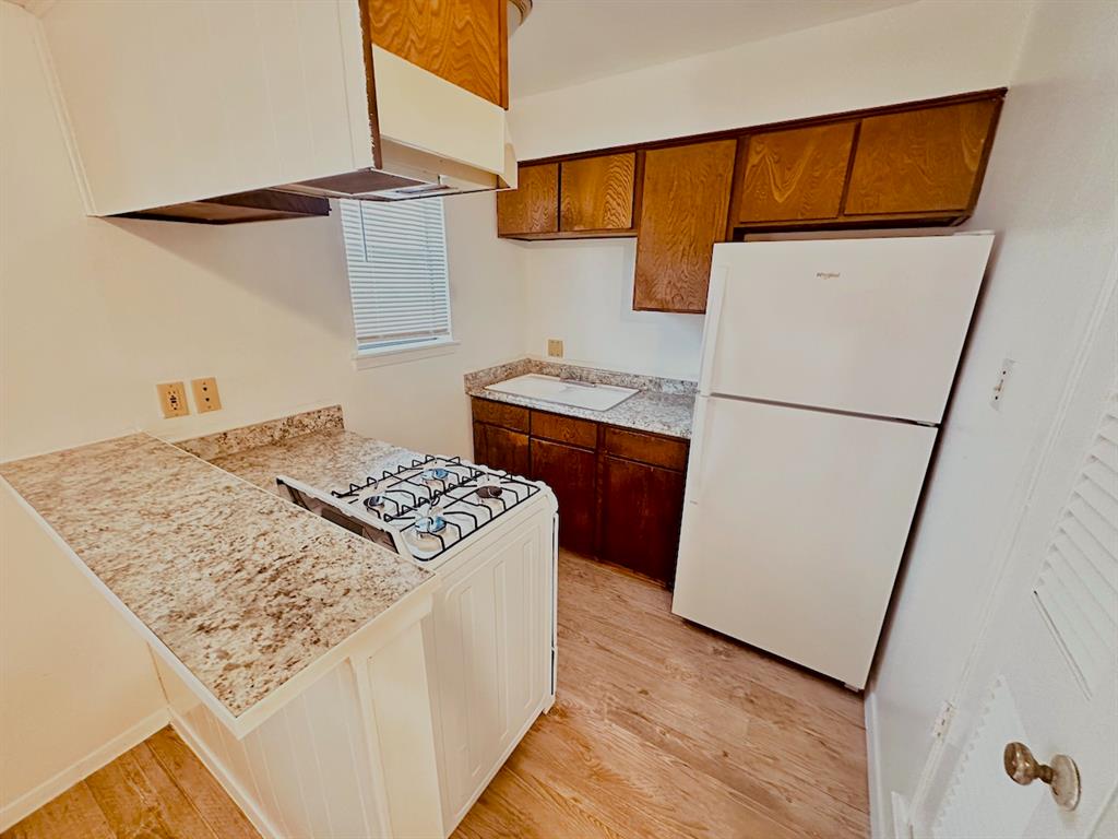 4204 Speedway, Unit 203 Austin, TX 78751 - Photo 3 of 10 Kitchen featuring light countertops, freestanding refrigerator, light wood finished floors, and brown cabinetry
