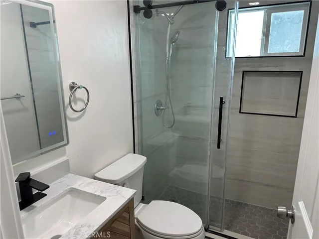 a bathroom with a granite countertop toilet a sink and shower
