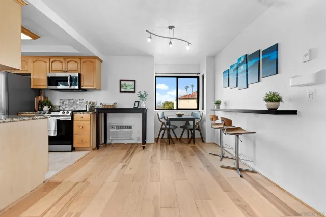 a kitchen with stainless steel appliances granite countertop a stove top oven a sink dishwasher a dining table and chairs with wooden floor