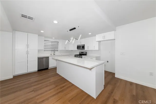 a kitchen with a sink a refrigerator and white cabinets