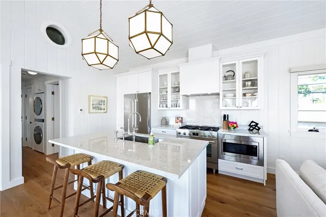 a kitchen with stainless steel appliances granite countertop a sink dishwasher a stove a refrigerator with a dining table and chairs with wooden floor