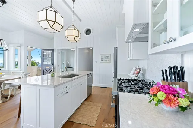 a kitchen with stainless steel appliances a stove a chimney a sink and cabinets