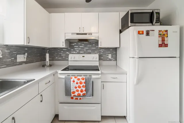 a utility room with stainless steel appliances white cabinets and a sink