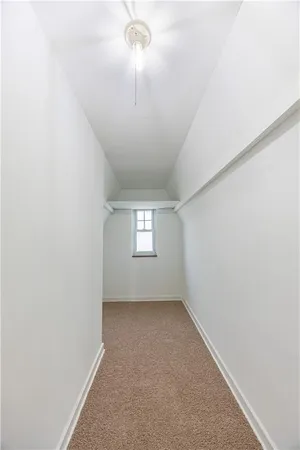 an empty room with a chandelier fan and windows