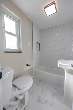 a white toilet sitting next to a bath tub